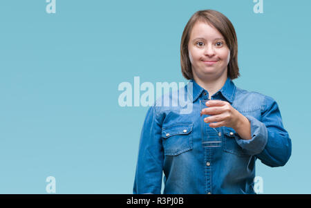 Young adult woman with down syndrome drinking water over isolated background with a happy face standing and smiling with a confident smile showing tee Stock Photo