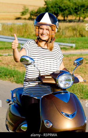 young woman with thumbs up on the motorroler Stock Photo