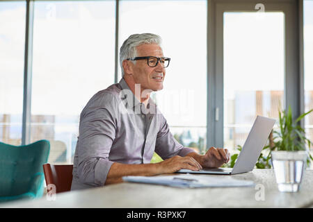 Mature man using laptop on table at home Stock Photo