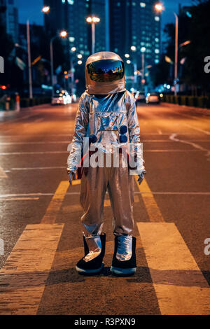 Spaceman standing on a street in the city at night Stock Photo