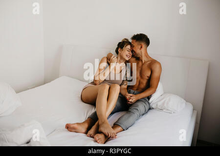 Happy young couple sitting in bed Stock Photo