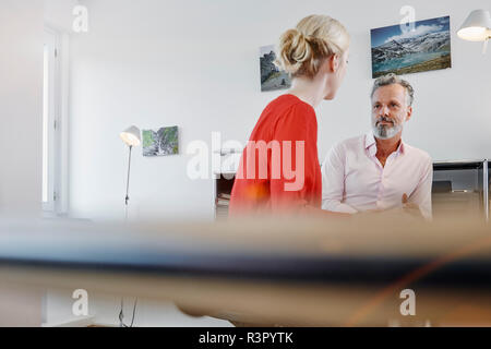 Two colleagues talking at desk in office Stock Photo