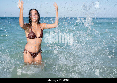 Happy carefree young woman splashing in the sea Stock Photo