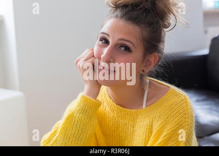 Portrait of smiling young woman with nose piercing wearing yellow pullover Stock Photo