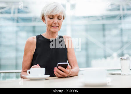 Senior woman using cell phone in a cafe Stock Photo