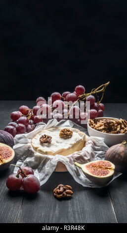 concept of appetizers for wine, camembert cheese, dark grapes, walnuts and figs with honey, on a wooden rustic background  space for text Stock Photo