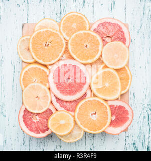 sliced oranges, lemons and grapefruits, on a wooden tray, against the background of a wooden table, the concept of useful citrus fruits Stock Photo