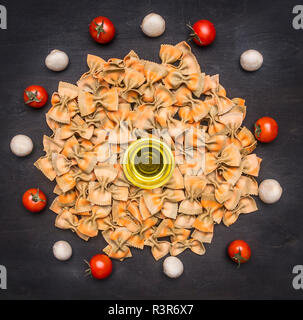 Raw Italian pasta with cherry tomatoes, mushrooms and butter, lined round on a rustic wooden background Stock Photo