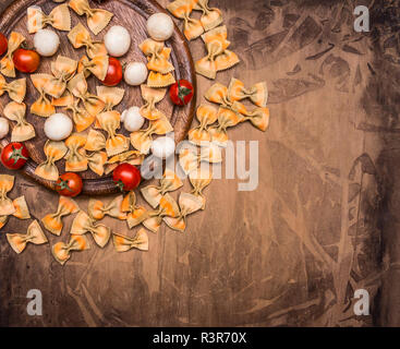 Concept of cooking Italian vegetarian pasta with cherry tomatoes, herbs, champignons seasoning and butter on a circular cutting board, space for text, Stock Photo