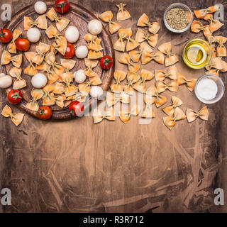 Vegetarian pasta with cherry tomatoes, herbs and seasonings, ingredients lined on a round cutting board, space for text, border Stock Photo