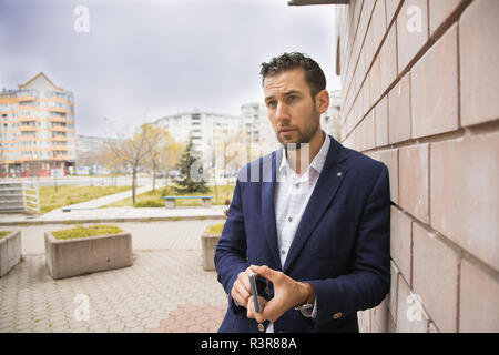 A young handsome businessman leaning on the wall. Stock Photo
