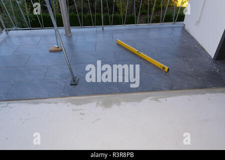 Balcony floor tiles installation. Laying tiles from porcelain. Interior remodeling theme. Stock Photo