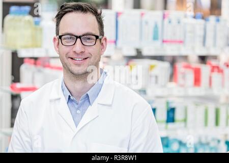 Portrait of young male pharmacist standing in pharmacy. Stock Photo