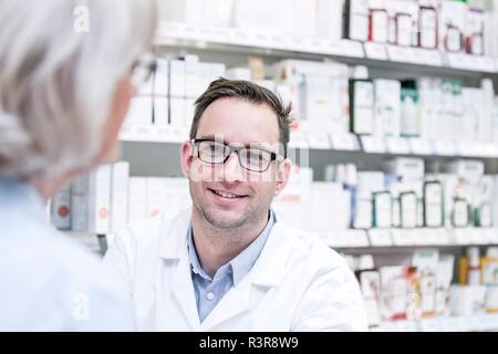 Male pharmacist talking with senior customer in pharmacy. Stock Photo