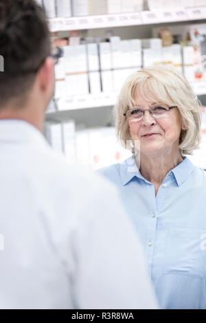 Senior female customer talking to male pharmacist in pharmacy. Stock Photo