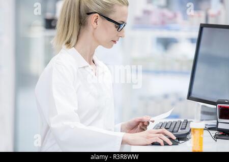 Female pharmacist working on computer in pharmacy. Stock Photo