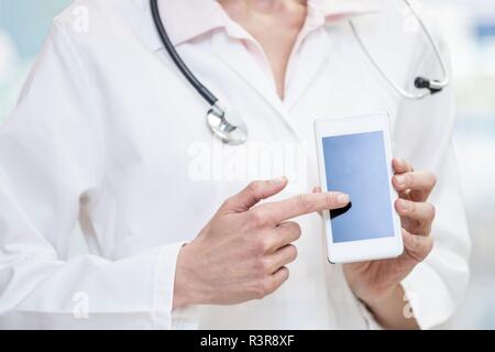 Doctor pointing at mobile phone screen. Stock Photo