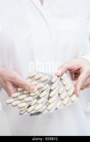Close-up of pharmacist holding pills in blister packs. Stock Photo