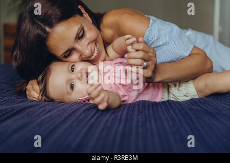 Happy mother cuddling with her baby girl on bed Stock Photo