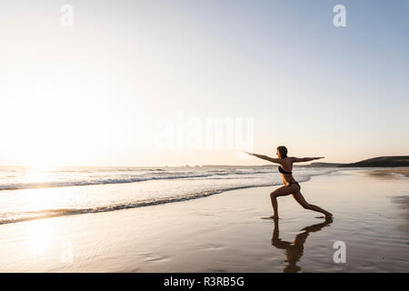 Young woman practicing yoga on the beach Stock Photo