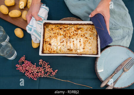 Woman serving potato mincemeat gratin, partial view Stock Photo