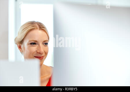 Portrait of smiling young woman working on computer Stock Photo