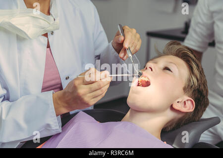 Dentist examining boy's teeth with dental instruments Stock Photo