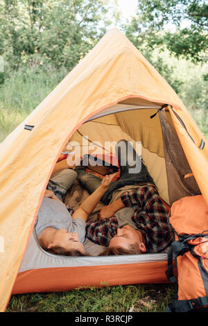 Young couple relaxing in tent, using digital tablet Stock Photo