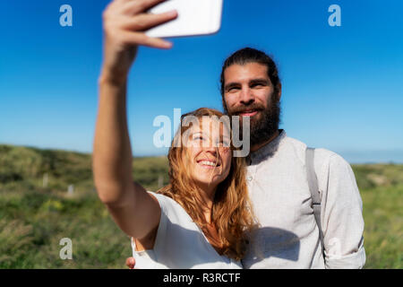 Young couple taking smartphone selfies on the beach Stock Photo