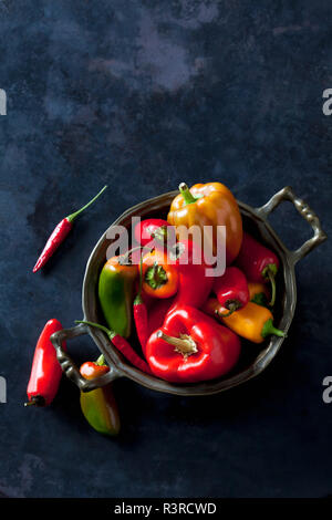 Bowl of various organic bell peppers and chili peppers on dark ground Stock Photo