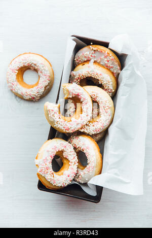 Cake pan of homemade doughnuts with icing and sugar beads Stock Photo