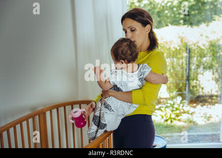 Mother putting her baby girl to bed Stock Photo