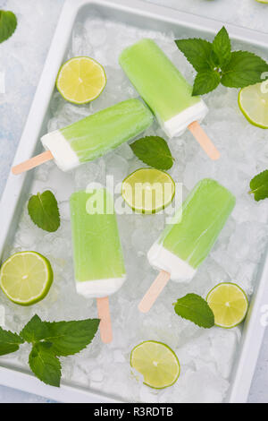 Lime mint popsicles, slices of limes and mint leaves on crushed ice Stock Photo