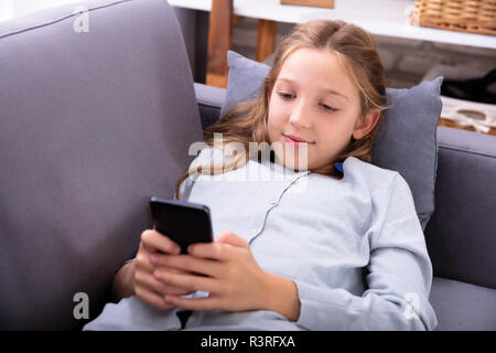 Portrait Of A Relaxed Girl On Sofa Using Mobile Phone Stock Photo