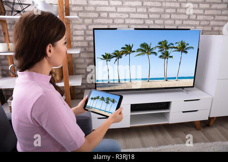 Side View Of A Young Woman Connecting Television Channel Through Wireless On Digital Tablet Stock Photo