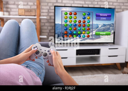 Woman Using Joystick While Playing Video Game On Television At Home Stock Photo