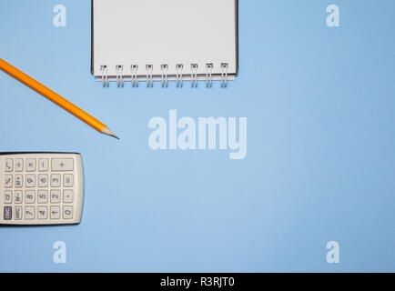 Notepad, calculator and pencil on blue background, top view Stock Photo