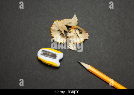 Sharpened pencil and sharpener on black background, top view Stock Photo