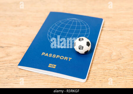small toy soccer ball and biometric passport on a wooden table Stock Photo