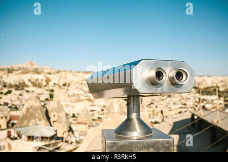 Binoculars on the viewing platform. Ahead is a blurred view of a city called Goreme in Cappadocia in Turkey. Sightseeing. Stock Photo