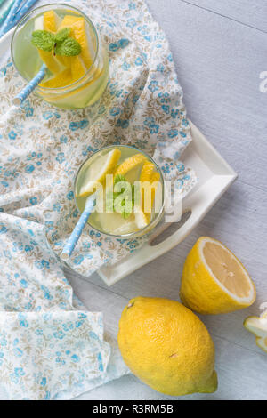 Summer citrus fruits drink on wooden background. Detox citrus infused flavored water. Refreshing summer homemade cocktail with lemon. Fresh lemon and  Stock Photo