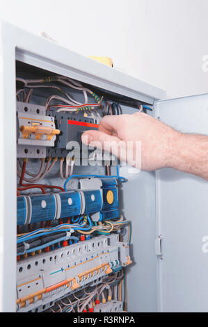 The man turns on the electric switch. Checking electrical equipment in the new building Stock Photo
