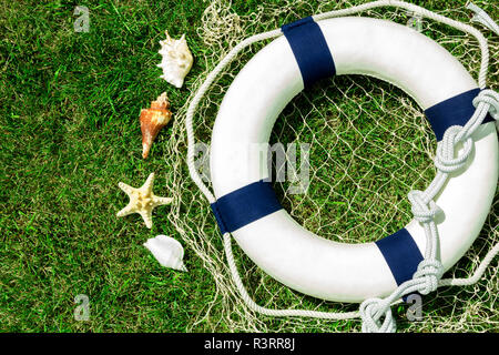 White lifebuoy on green lawn, space for text Stock Photo