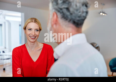 Smiling young woman looking at mature colleague in office
