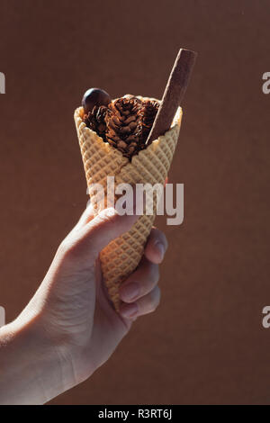 Woman's hand holding ice cream cone with autumnal filling Stock Photo