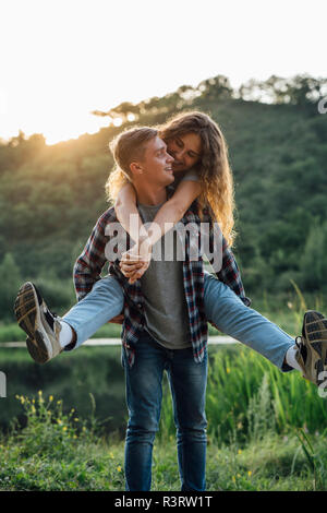 Romantic couple spending time in nature, embracing at sunset Stock Photo