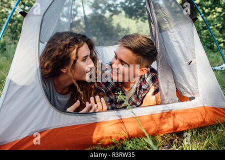 Happy young couple lying in tent, talking Stock Photo