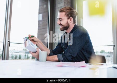 Smiling young man checking colour samples at desk in office Stock Photo