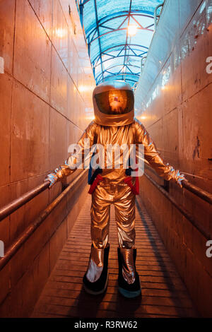Spaceman in the city at night standing in narrow passageway Stock Photo
