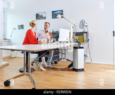 Two colleagues talking at desk in office Stock Photo